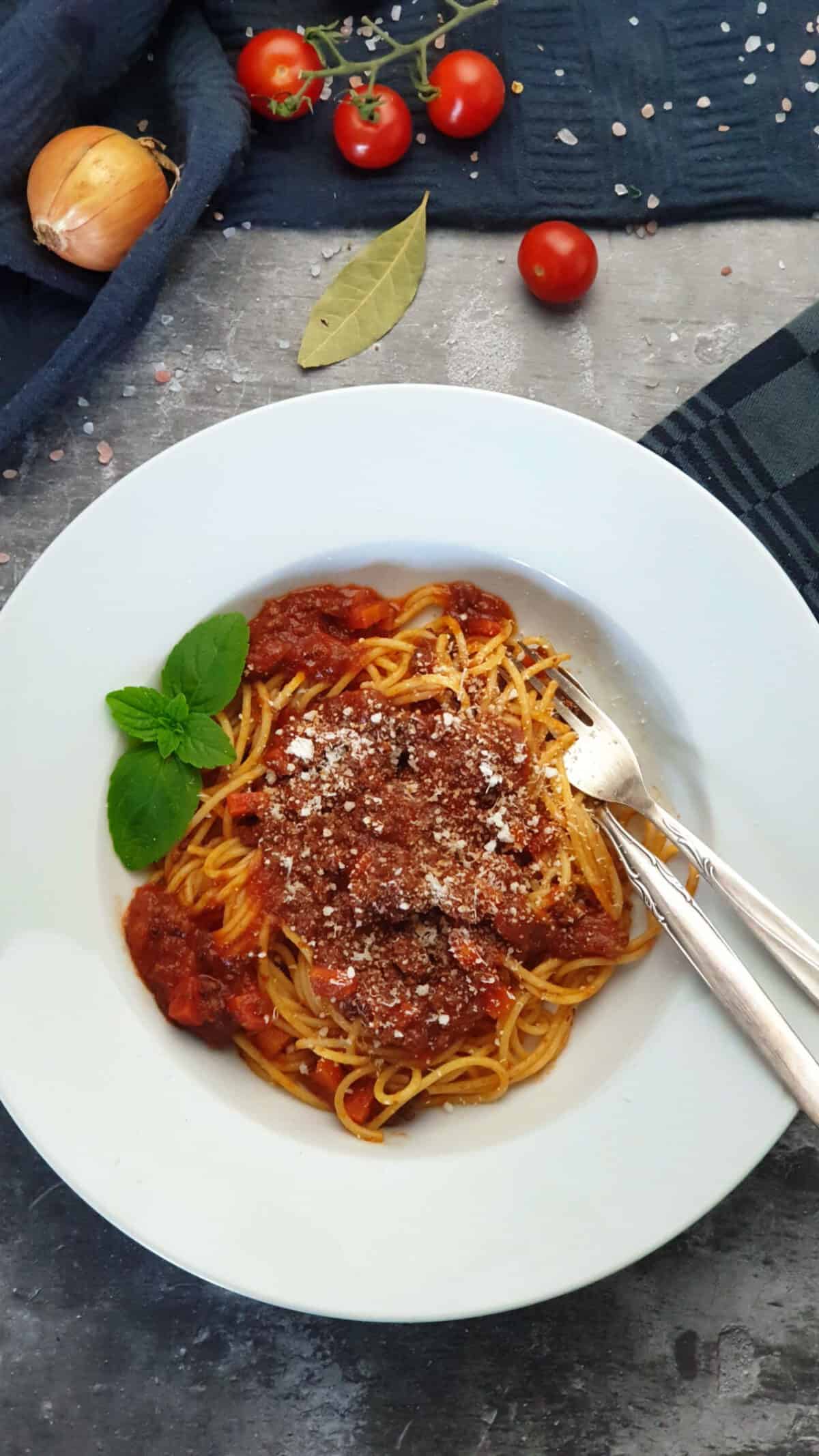 Auf einem hellen Teller angerichtet Blitz Bolognese mit Basilikum und Parmesan.