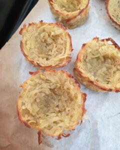 Gebackene Kartoffelnester aus der Muffinform auf einem Backpapier.