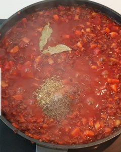 In einer Pfanne Tomaten-Hackfleisch Soße mit Lorbeerblättern und Gewürzen.