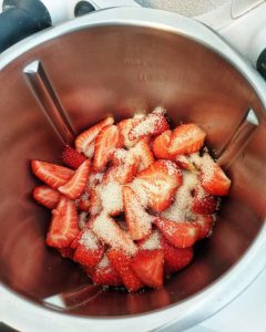 Im Thermomix Topf halbierte Erdbeeren mit Zucker.
