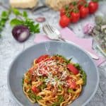 Pasta bella italia mit Hackfleischsoße, Rucola und frischen Tomaten dekarativ angerichtet mit Parmesan bestreut in einer grauen Schale