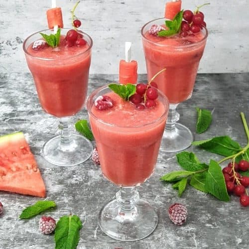 Ein erfrischendes Sommergetränk aus Wassermelone, Erdbeeren und Wasser, angerichtet in hohen Gläsern und mit Minze dekoriert