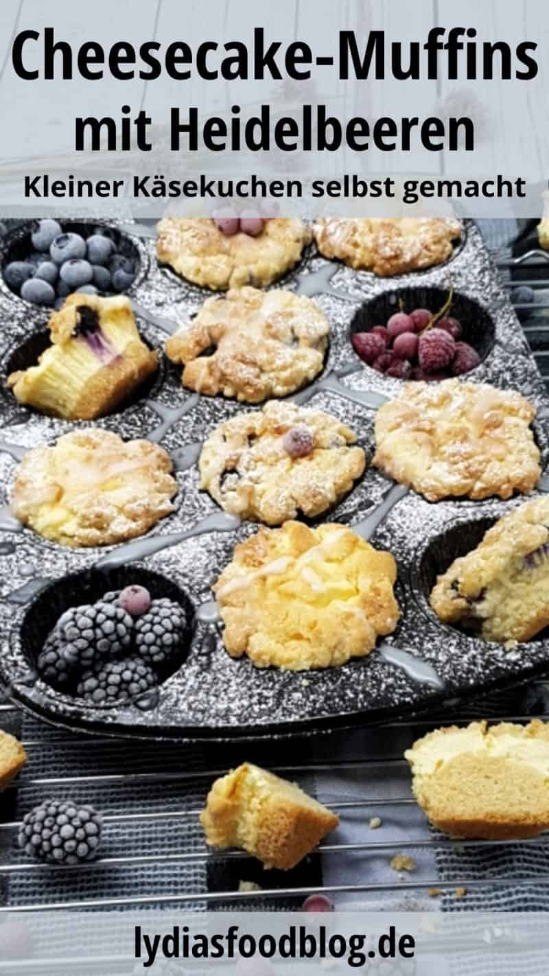 Cheesecake Muffins mit Heidelbeeren und Streuseln in der Muffinform dekorativ angerichtet, mit Zuckerguss und frischen Früchten dekoriert.