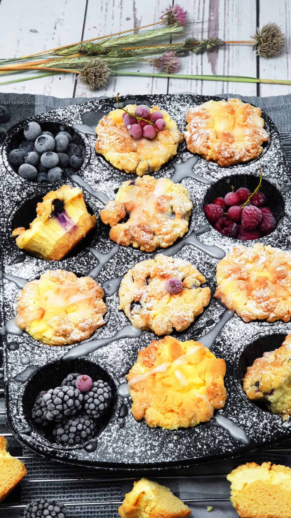 In einer Muffinform Cheesecake Muffins mit Heidelbeeren. Dekorativ angerichtet und fotografiert. Im Hintergrund Deko.
