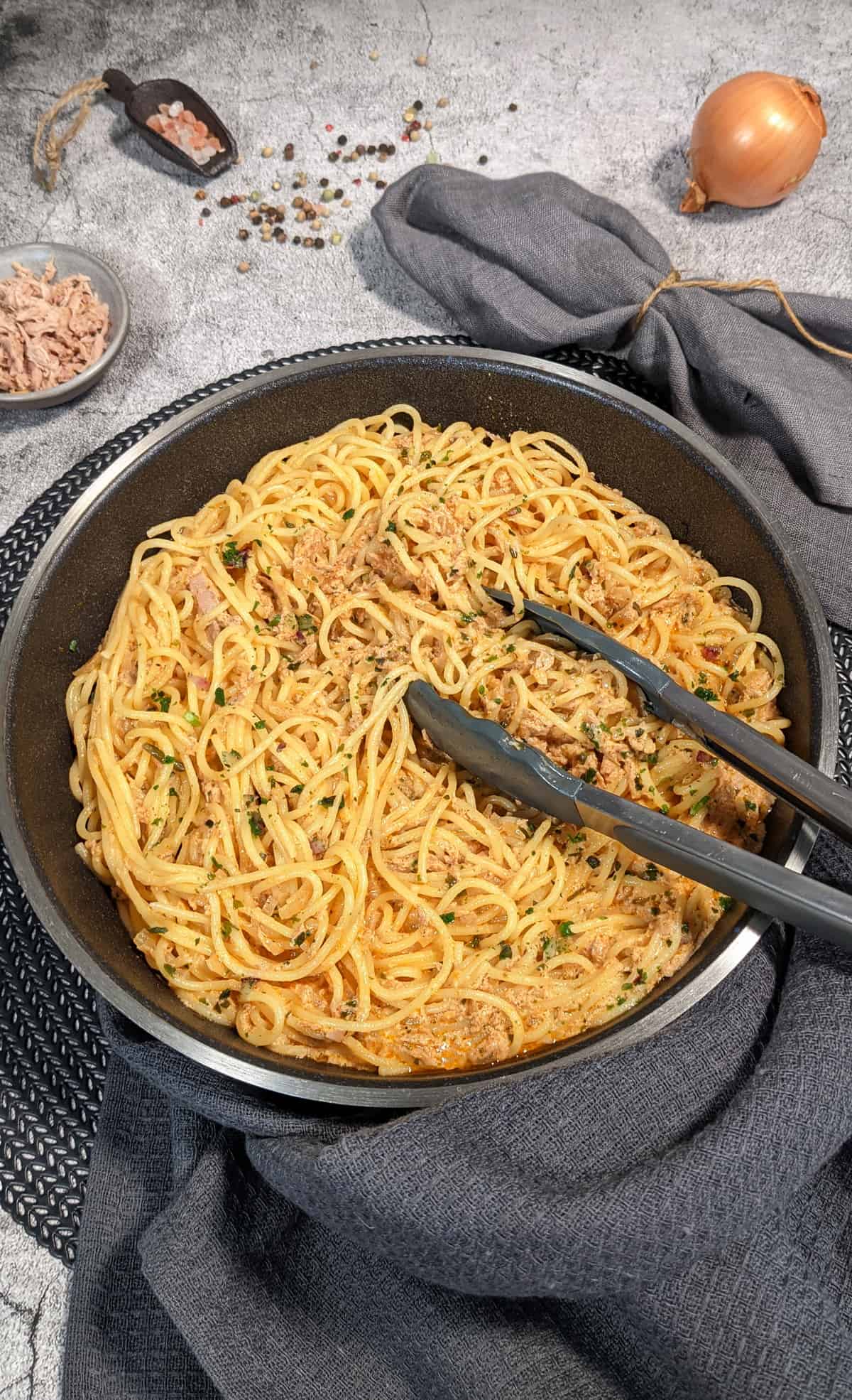 Spaghetti mit Thunfisch-Sahne-Soße angerichtet in einer Pfanne. Deko drumherum.