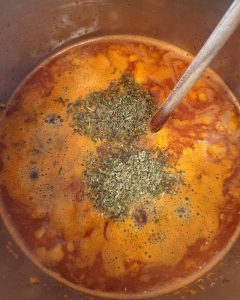 Ein Topf mit einer roten Suppe und Gewürzen.