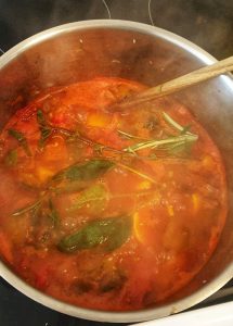 Kochende Suppe mit frischen Gewürzen in einem Topf.