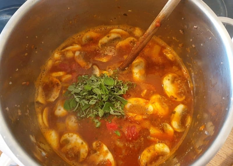 In einem Topf eine Suppe mit Hackfleisch und Pilzen.