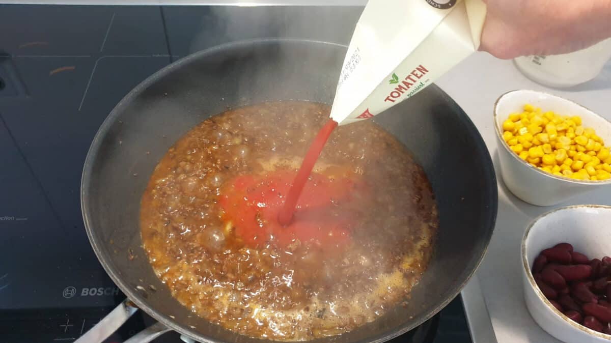 In einer Pfanne Hackfleisch mit Brühe und passierten Tomaten.