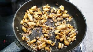 Angebratene Pilze mit Zwiebeln in einer Pfanne.