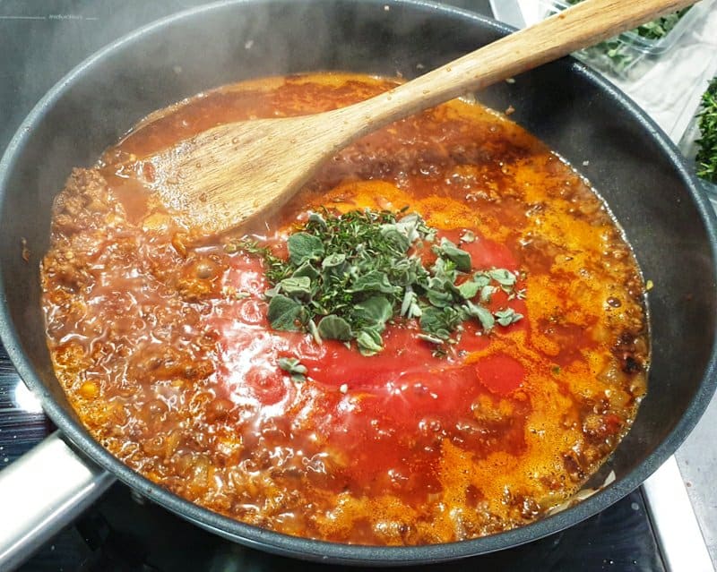 In einer Pfanne eine Tomaten Hackfleischsoße mit frischen Kräutern.