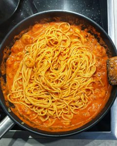 In einer Pfanne Spaghetti mit Shrimps in Tomatensoße.