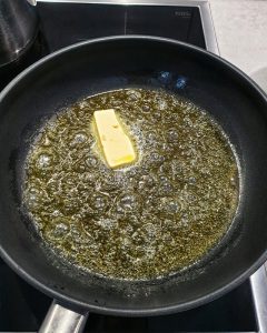 In einer Pfanne sieht man ein Stück Butter und Olivenöl.