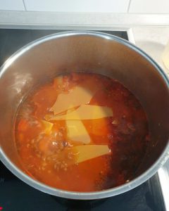 In einem Topf kochend eine Lasagne-Suppe mit zerbrochenen Lasagne Platten.
