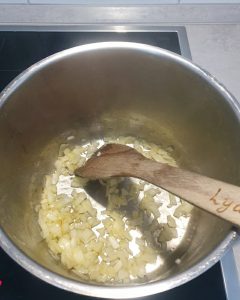 In einem Topf werden Zwiebeln in Olivenöl angedünstet für die Kartoffelsuppe.