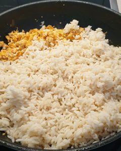 Der vorgekochte Reis kommt zu dem Rührei in die Pfanne.
