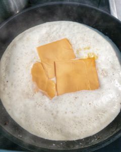 Sahne Soße mit Chester Käse in einer Pfanne.