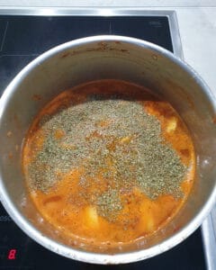 In einem Topf eine rote Suppe mit Kartoffeln und Gewürzen.
