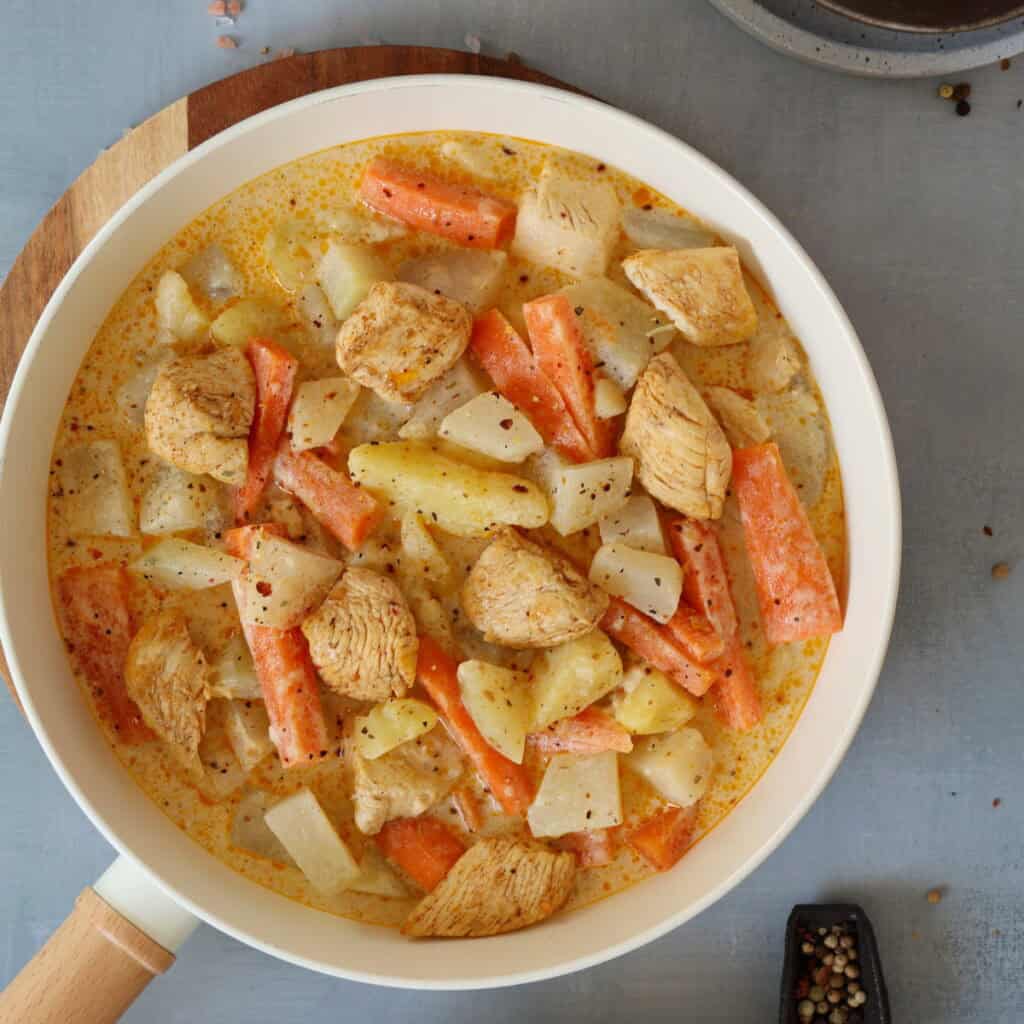 Fertige Kohlrabi Hähnchen Pfanne mit Kartoffeln, Möhren und Hähnchenstücken in cremiger Soße, von oben fotografiert.